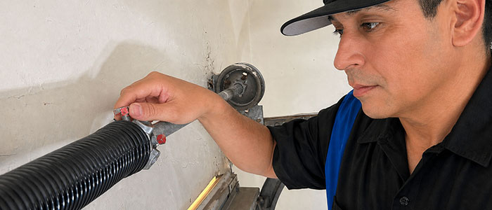 Garage door repair technician repacing a broken torsion spring in San Diego CA.